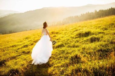 Doğaya poz veren beyaz elbiseli güzel gelin