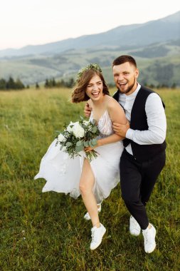 Güzel, genç, aşık bir çift dağların arka planında poz veriyor.