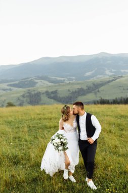 Güzel, genç, aşık bir çift dağların arka planında poz veriyor.