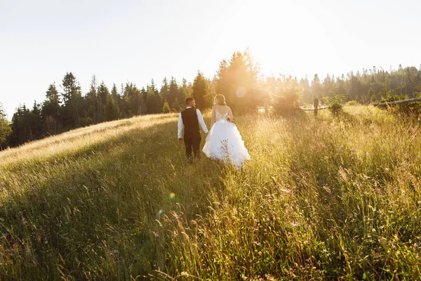 森の中に花束を持った白いドレスを着た美しい花嫁と新郎 — ストック写真