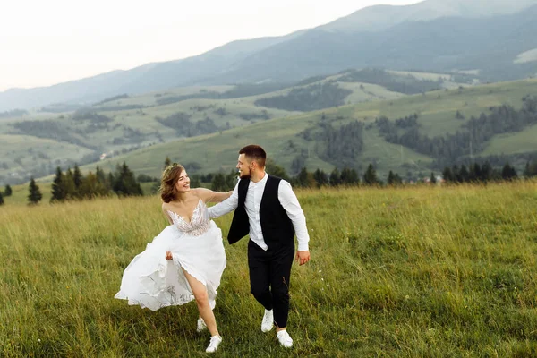 Güzel, genç, aşık bir çift dağların arka planında poz veriyor.