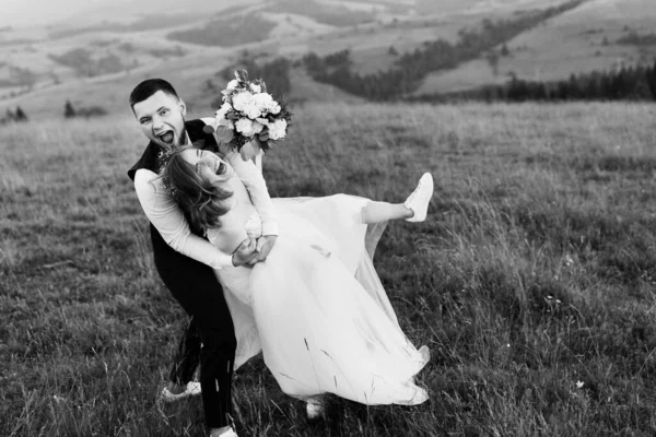 Güzel, genç, aşık bir çift dağların arka planında poz veriyor.