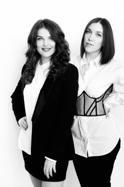 Stüdyoda poz veren şık takım elbiseli güzel iş kadınlarının siyah beyaz portresi.