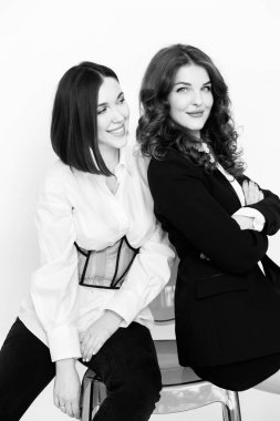 Stüdyoda poz veren şık takım elbiseli güzel iş kadınlarının siyah beyaz portresi.