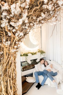 Genç aşık çift oturma odasındaki kanepede oturuyor.