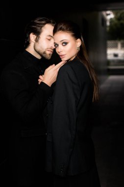 Siyahlar içinde dergi kapağı için fotoğraf çeken beyaz bir çift. Çekici sakallı genç kadın kameraya poz veriyor, manken konsepti.. 