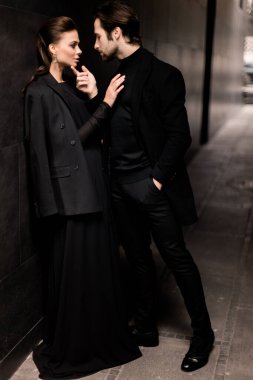 Siyahlar içinde dergi kapağı için fotoğraf çeken beyaz bir çift. Çekici sakallı genç kadın kameraya poz veriyor, manken konsepti.. 