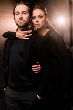 Siyahlar içinde dergi kapağı için fotoğraf çeken beyaz bir çift. Çekici sakallı genç kadın kameraya poz veriyor, manken konsepti.. 