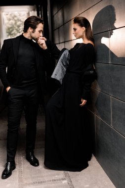 Siyahlar içinde dergi kapağı için fotoğraf çeken beyaz bir çift. Çekici sakallı genç kadın kameraya poz veriyor, manken konsepti.. 