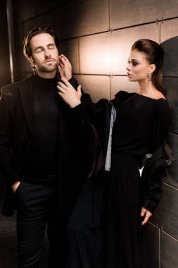 Siyahlar içinde dergi kapağı için fotoğraf çeken beyaz bir çift. Çekici sakallı genç kadın kameraya poz veriyor, manken konsepti.. 