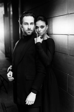 Siyahlar içinde dergi kapağı için fotoğraf çeken beyaz, şık giyinmiş beyaz bir çift resmi. Çekici sakallı genç kadın kameraya poz veriyor, manken konsepti.. 