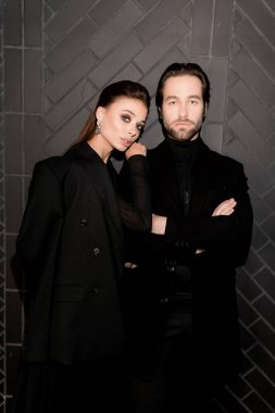 Siyahlar içinde dergi kapağı için fotoğraf çeken beyaz bir çift. Çekici sakallı genç kadın kameraya poz veriyor, manken konsepti.. 