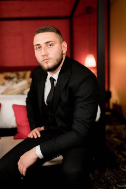 Takım elbiseli ve siyah ceketli yakışıklı bir gencin portresi.