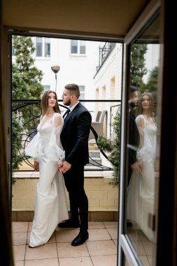 Gelin ve damat düğün gününde balkonda poz veriyorlar.