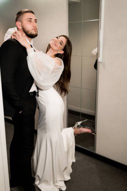 Güzel gelin ve damat aynanın yanında poz veriyor.