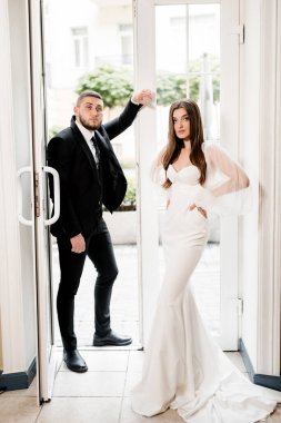 Güzel, genç ve aşık bir çift pencerenin yanında poz veriyor.