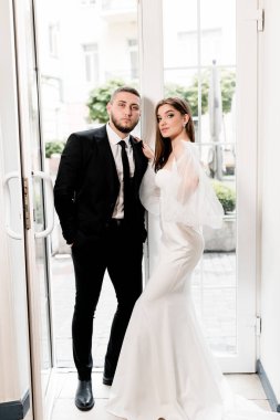 Güzel, genç ve aşık bir çift pencerenin yanında poz veriyor.