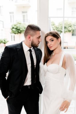 Güzel, genç ve aşık bir çift pencerenin yanında poz veriyor.