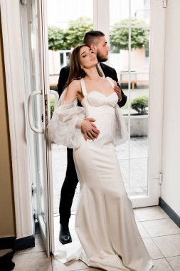 Güzel, genç ve aşık bir çift pencerenin yanında poz veriyor.