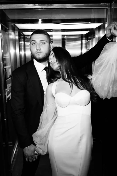black and white photo of bride and groom posing in the lift