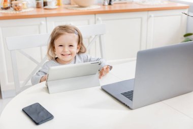 Laptop ve tablet bilgisayarı olan sevimli küçük bir kız.