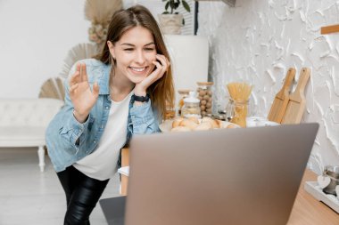 Mutfakta dizüstü bilgisayarı olan güzel genç bir kadın.