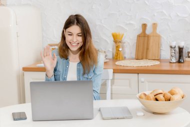 Mutfakta dizüstü bilgisayarı olan güzel genç bir kadın.