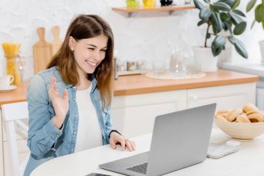 Mutfakta dizüstü bilgisayarı olan güzel genç bir kadın.