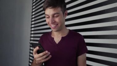 Kazanan teklifi kutlamak ya da akıllı telefondan ecommerce alışveriş teklifi almak. Heyecanlı genç adam cep telefonuna bakarak başarıyı kutlayan bir uygulama kullanıyor, evet kazanan hareketi. Yakışıklı adam kamerada mutlu görünüyor. 