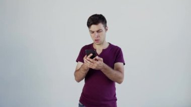 Akıllı telefon ekranına bakan hoşnutsuz genç adam, kötü haber mesajları, spam veya dolandırıcılık mesajlarından memnun değil. Mutsuz, stresli erkek mobil uygulama kullanıcısı e-postada phishing linki alıyor veya online kumarhanede kayboluyor, bahis kazanamadı