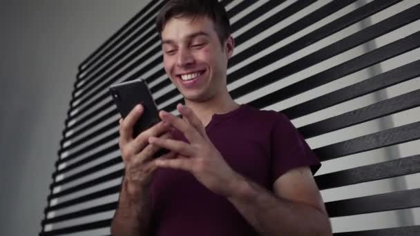 Νέος Όμορφος Μαθητής Νεαρός Άνδρας Γιορτάζει Νίκη Χρησιμοποιώντας Smartphone Του — Αρχείο Βίντεο