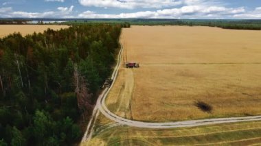 Buğday tarlasında askeri tankın havadan görünüşü. İnsansız hava aracı uçuşu buğday tarlasında çalışan hasat makinesini patlama kraterleri ve kabuk kraterleriyle birleştirdi. Yemek krizi. Ukrayna 'da savaş. Dünya gıda kıtlığı