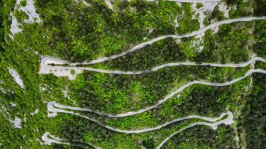 Dağ yılanbalığı yolunun yukarıdan görünüşü ve hareket eden birçok araba. Yokuş yukarı, keskin virajlar. Arabalar dağ yolunda ilerler.