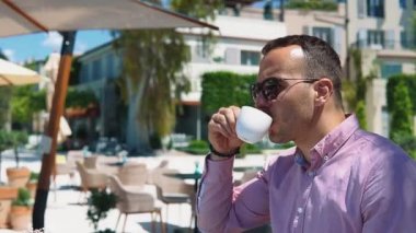 Kafkasyalı genç ve başarılı iş adamının portresi. Deniz kenarındaki bir restoranda kahve içiyor.