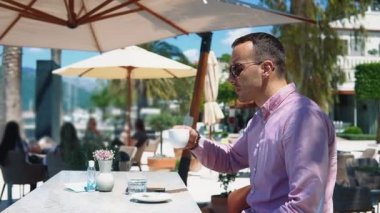 Kafkasyalı genç ve başarılı iş adamının portresi. Deniz kenarındaki bir restoranda kahve içiyor.