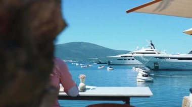 Kafkasyalı genç ve başarılı iş adamının portresi. Deniz kenarındaki bir restoranda kahve içiyor.