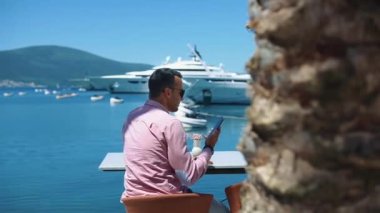 Kafkasyalı genç ve başarılı iş adamının portresi. Deniz kenarındaki bir restoranda kahve içiyor.