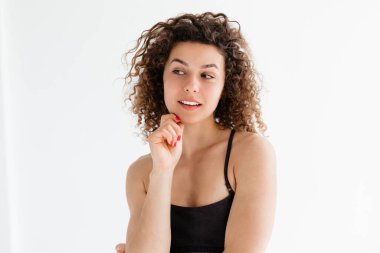 Güzel kıvırcık kız beyaz arka planda gülüyor.