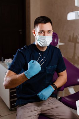 Dişçi aletleri parmaklarının arasında tutar.