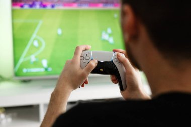 Adam konsolda futbol oynuyor.