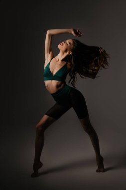 Stüdyoda yeşil spor kıyafetli ince atletik kız var.