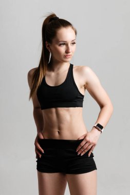 Siyah spor kıyafetleri içinde kabartmalı karın kasları olan atletik bir kız.