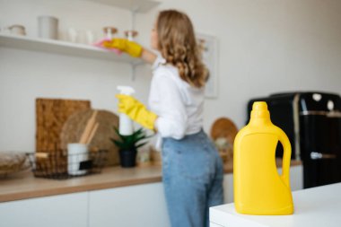 Beautiful girl wipes the shelves in the kitchen. High quality photo