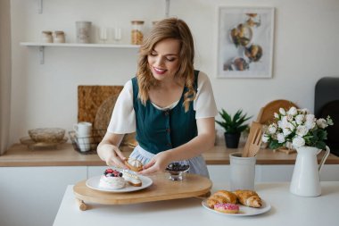 Girl shifts cakes on a dish in the kitchen. High quality photo