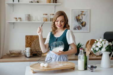 Beautiful girl housewife cooks in the kitchen. High quality photo