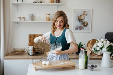 Beautiful girl housewife cooks in the kitchen. High quality photo