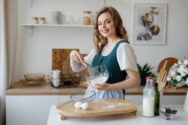 Beautiful girl housewife cooks in the kitchen. High quality photo
