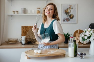 Beautiful girl housewife cooks in the kitchen. High quality photo