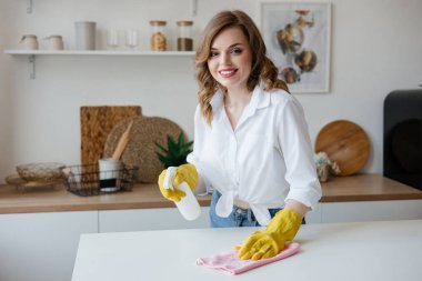 Housewife in yellow gloves wipes the kitchen table. High quality photo