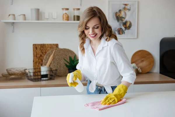 Housewife in yellow gloves wipes the kitchen table. High quality photo